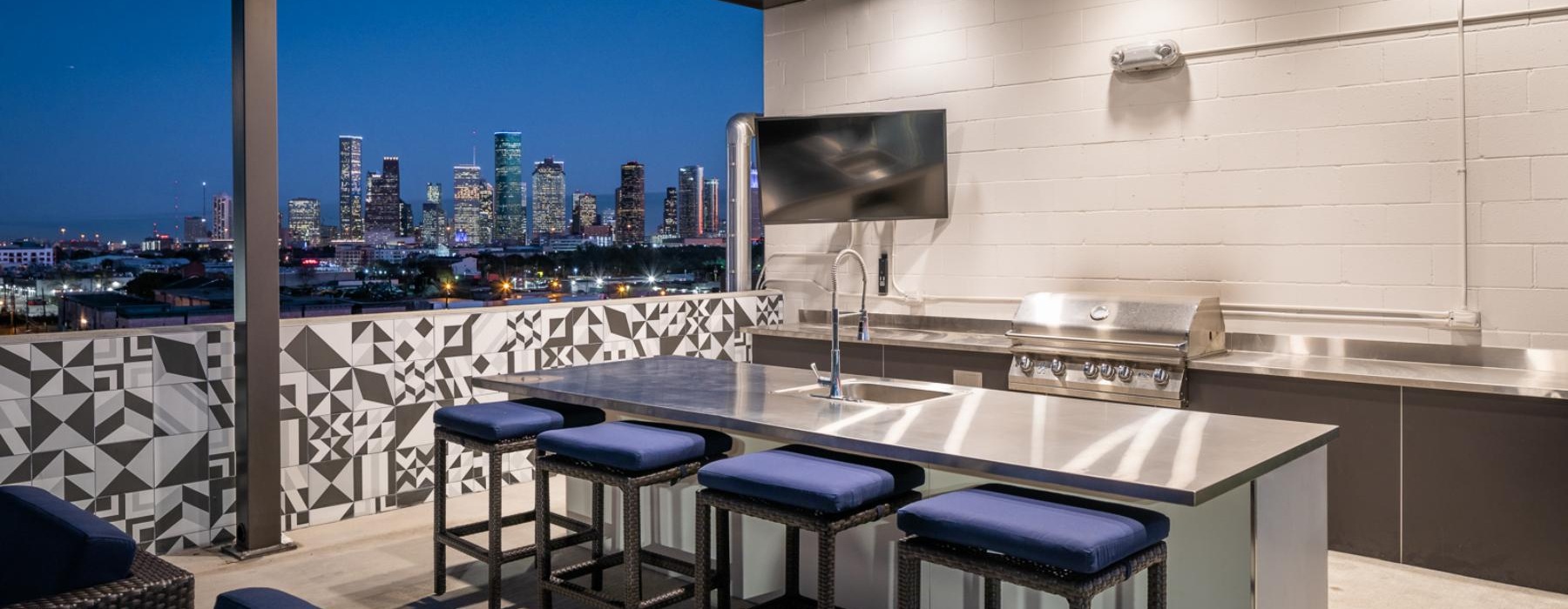 an outdoor kitchen with a tv and chairs